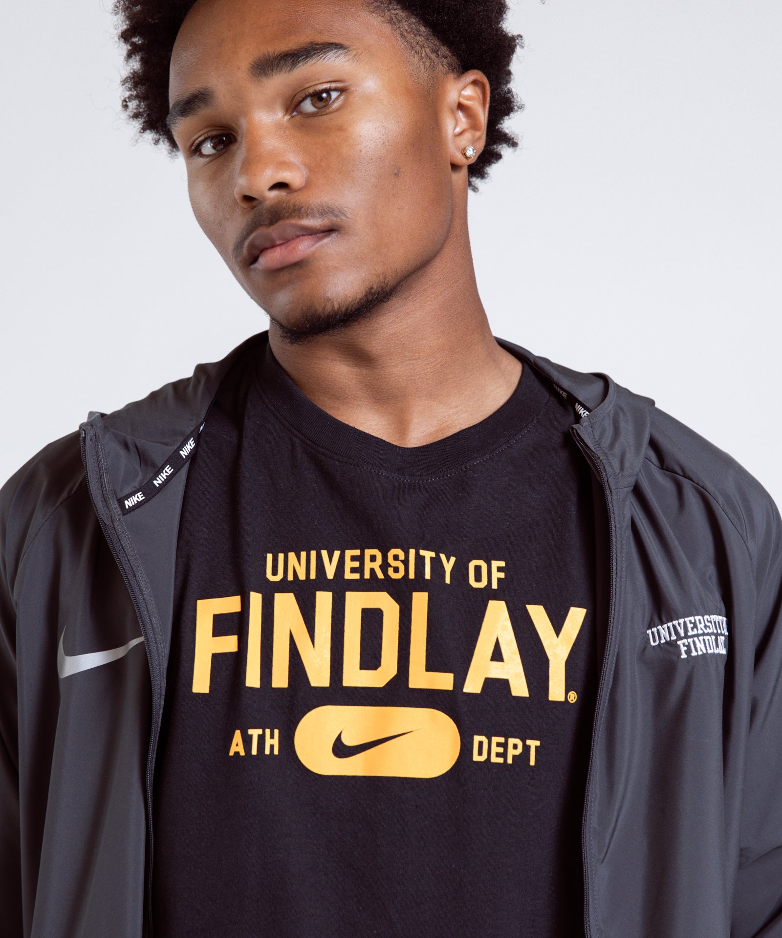 Person wearing a black 'University of Findlay' t-shirt with a gray jacket.