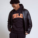 Person wearing a black hoodie with 'FINELAND' text and a leather jacket on a plain background