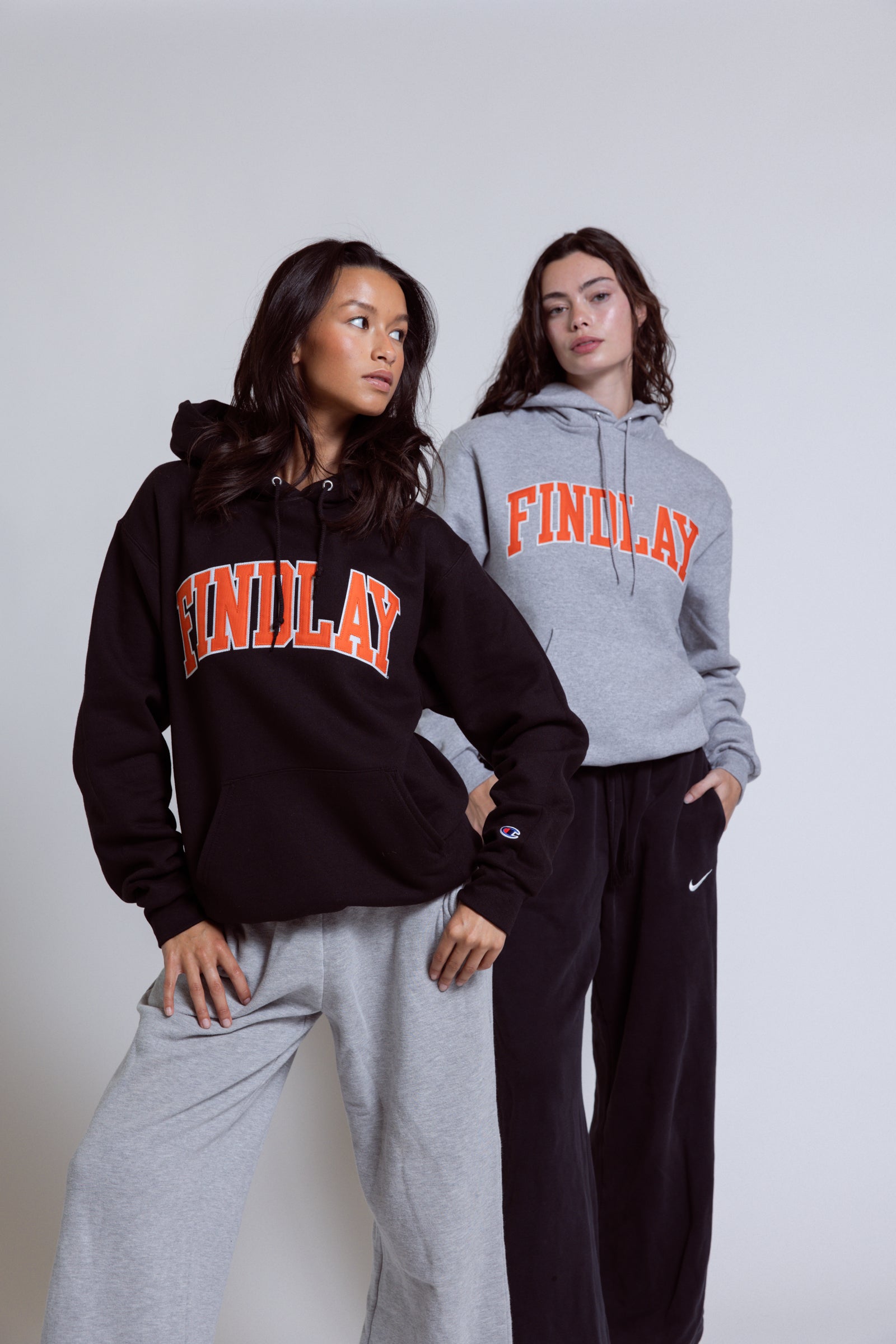Three women wearing orange and black t-shirts with a logo on a white background
