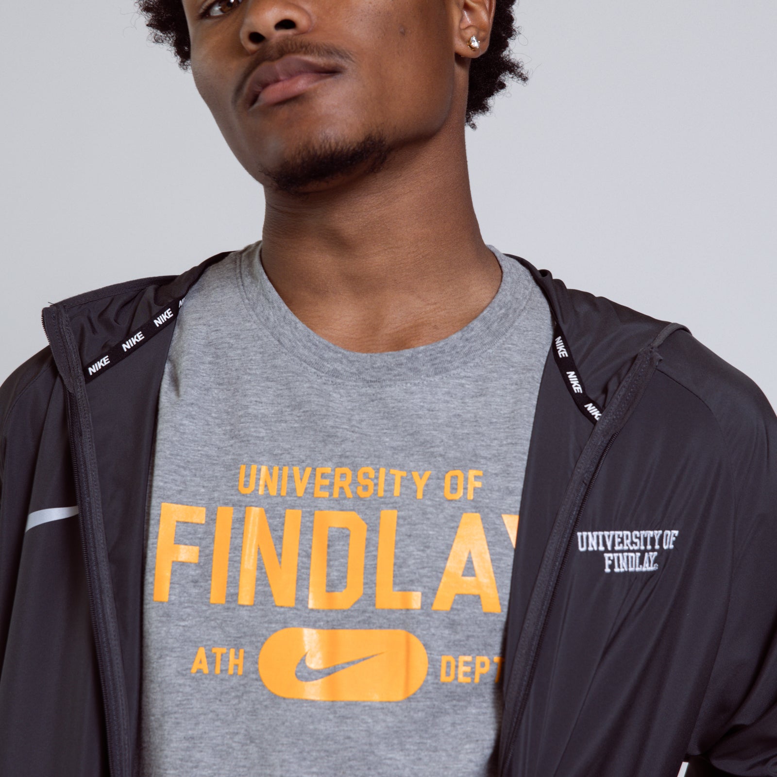 Person wearing a gray 'University of Findlay' t-shirt with a black jacket.